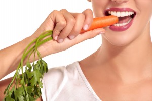 Girl in a white shirt bites carrot