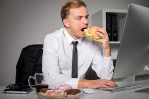 Busy man at the office eating fast food