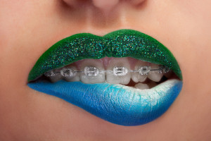Close up mouth blue and green lips with glitter brackets